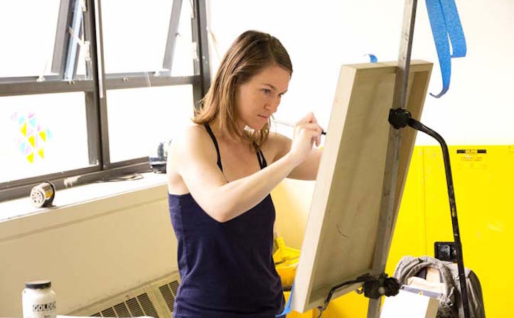 Student painting on canvas with window in background