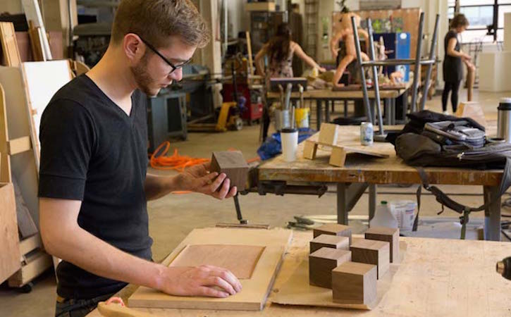 Student working on sculpture with wood