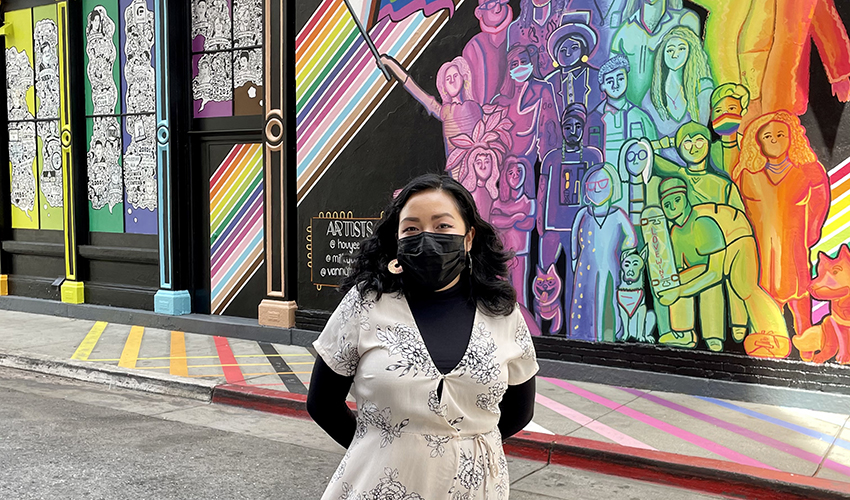 Artist and alumna Houyee Chow stands in front of the mural she painted in San Jose’s Qmunity District.