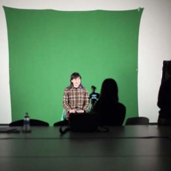 Green screen hanging with student sitting in front of it